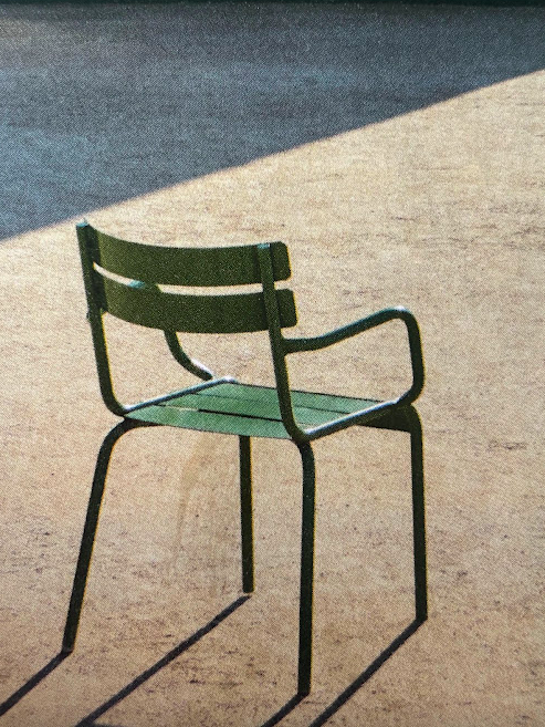 A green garden chair and its long shadow